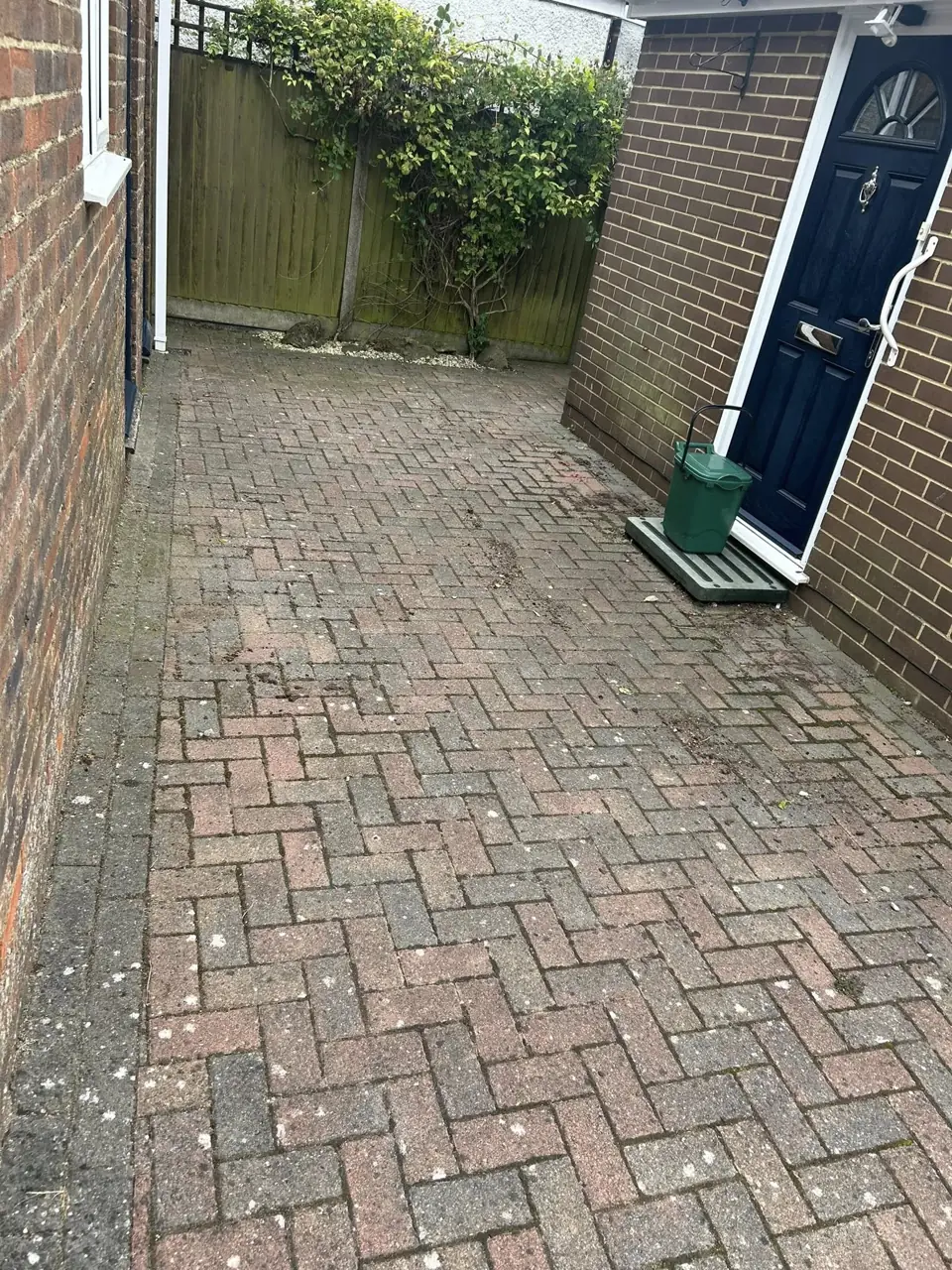 Herringbone block paved side path pressure washed clean beside a house