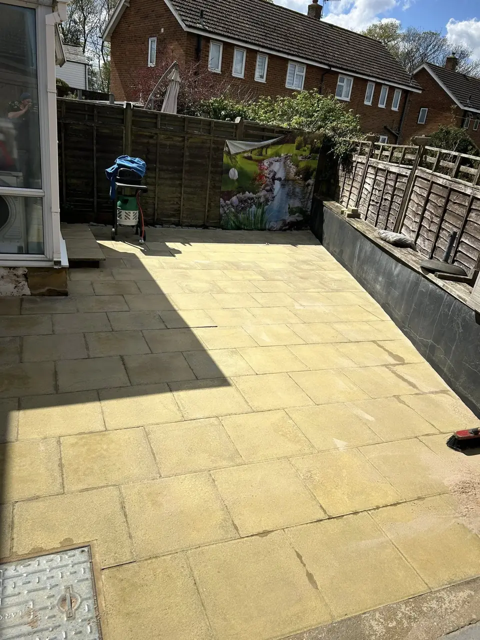 Buff paving slab patio cleaned and bright, with a fence and decking behind