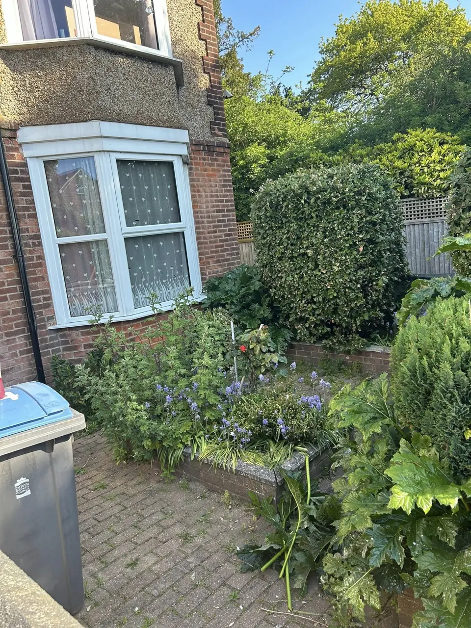 Front garden with planting and a path outside a bay fronted house