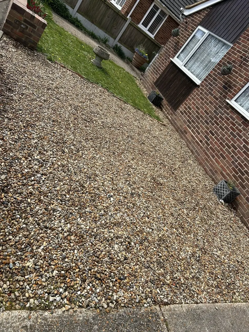 Gravel driveway raked level beside a red brick house