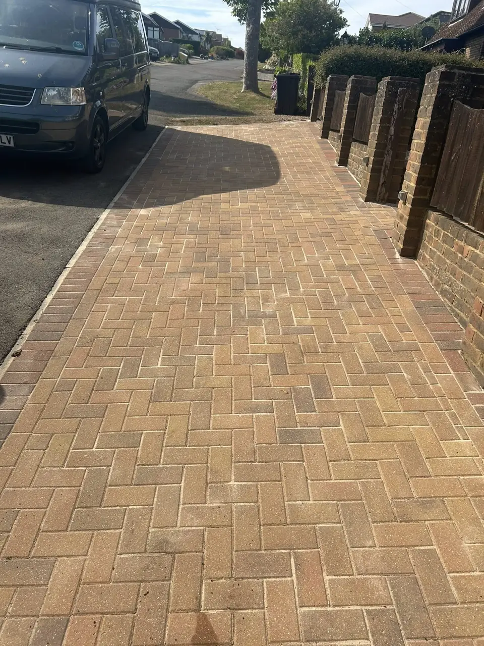 Long block paved path pressure washed clean beside a fence and parked van