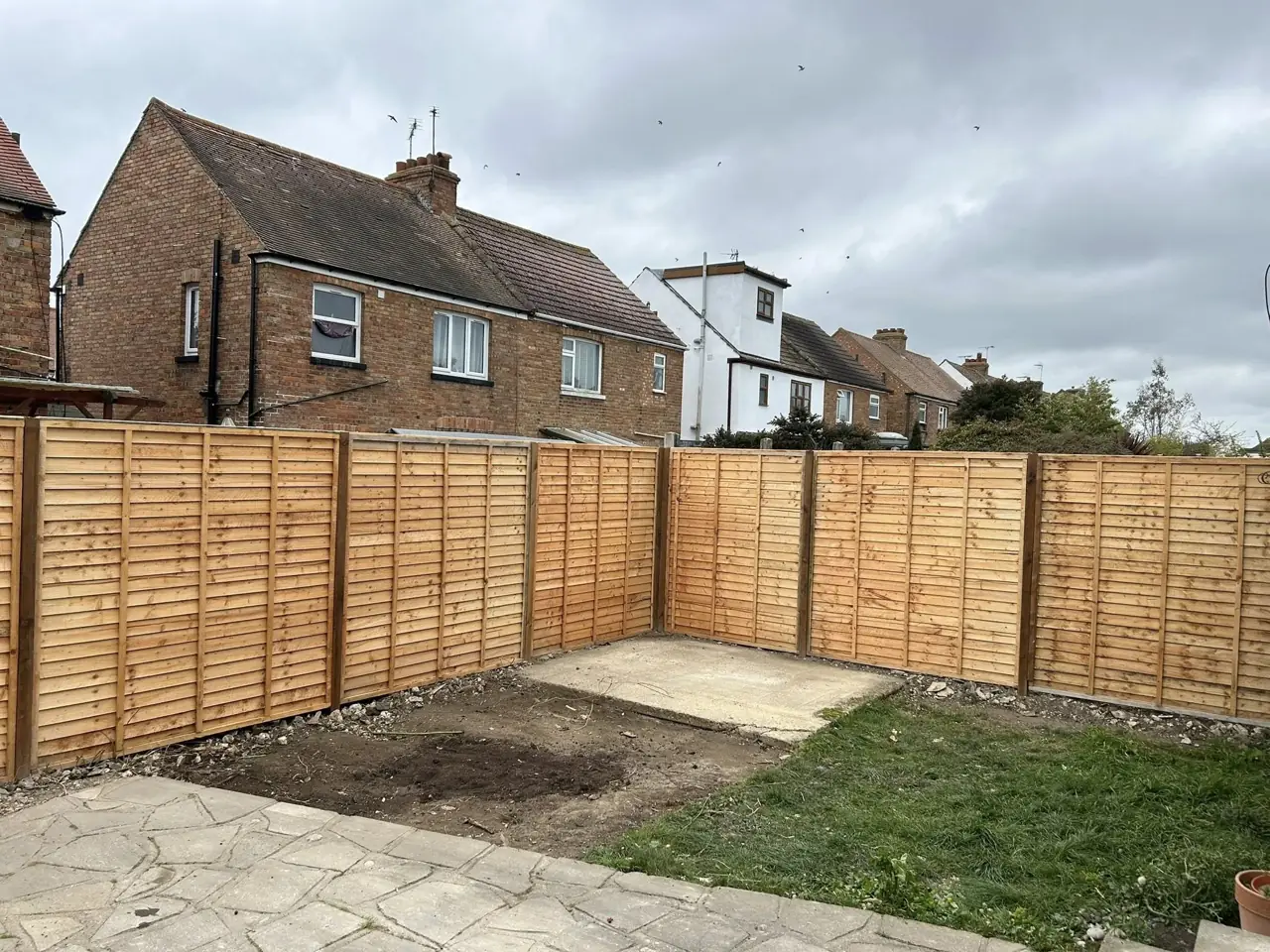 New lap fence panels and concrete posts fitted along a back garden boundary
