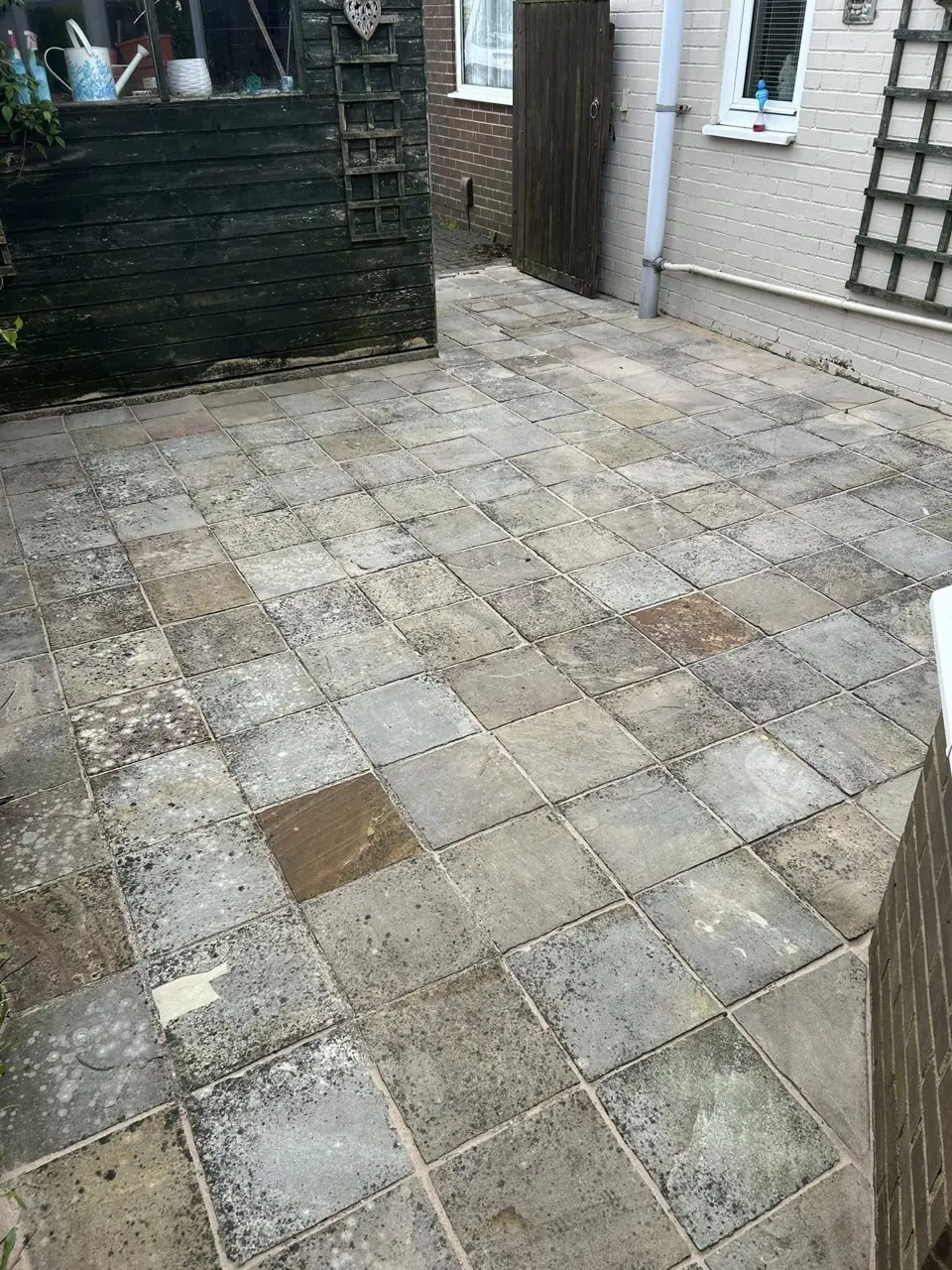 Patio slabs beside a house cleaned of dirt and algae